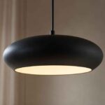 Czarna, owalna lampa wisząca z jasnym światłem w eleganckim wnętrzu