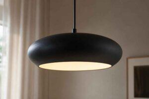 Czarna, owalna lampa wisząca z jasnym światłem w eleganckim wnętrzu