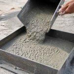 Mokry beton wylewany z metalowego pojemnika do stalowej formy budowlanej