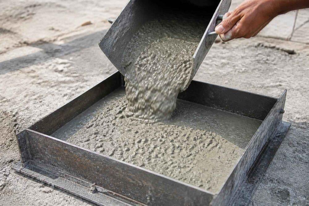 Mokry beton wylewany z metalowego pojemnika do stalowej formy budowlanej